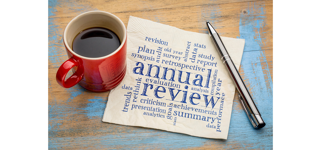 coffee mug and pen on table, paper with annual review written on it