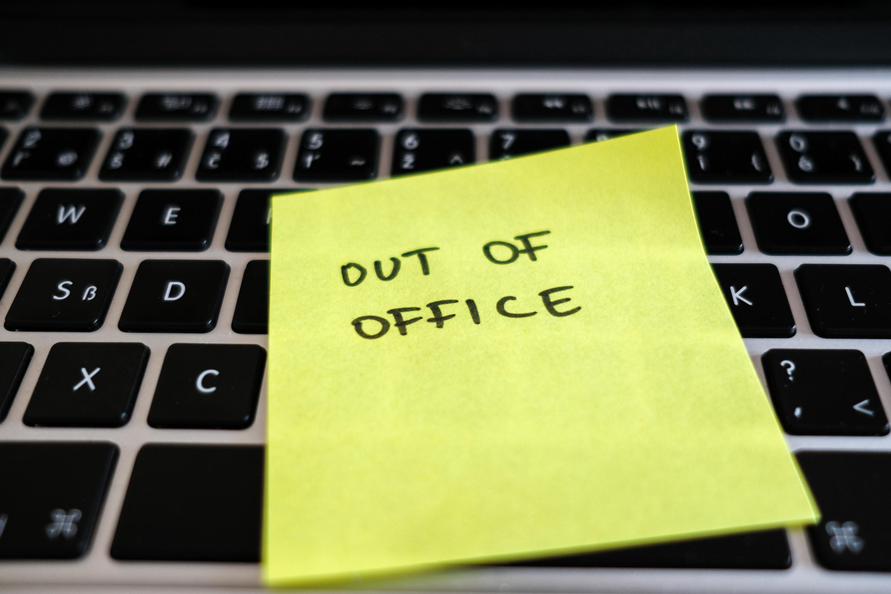 out of office written on sticky note on top of keyboard