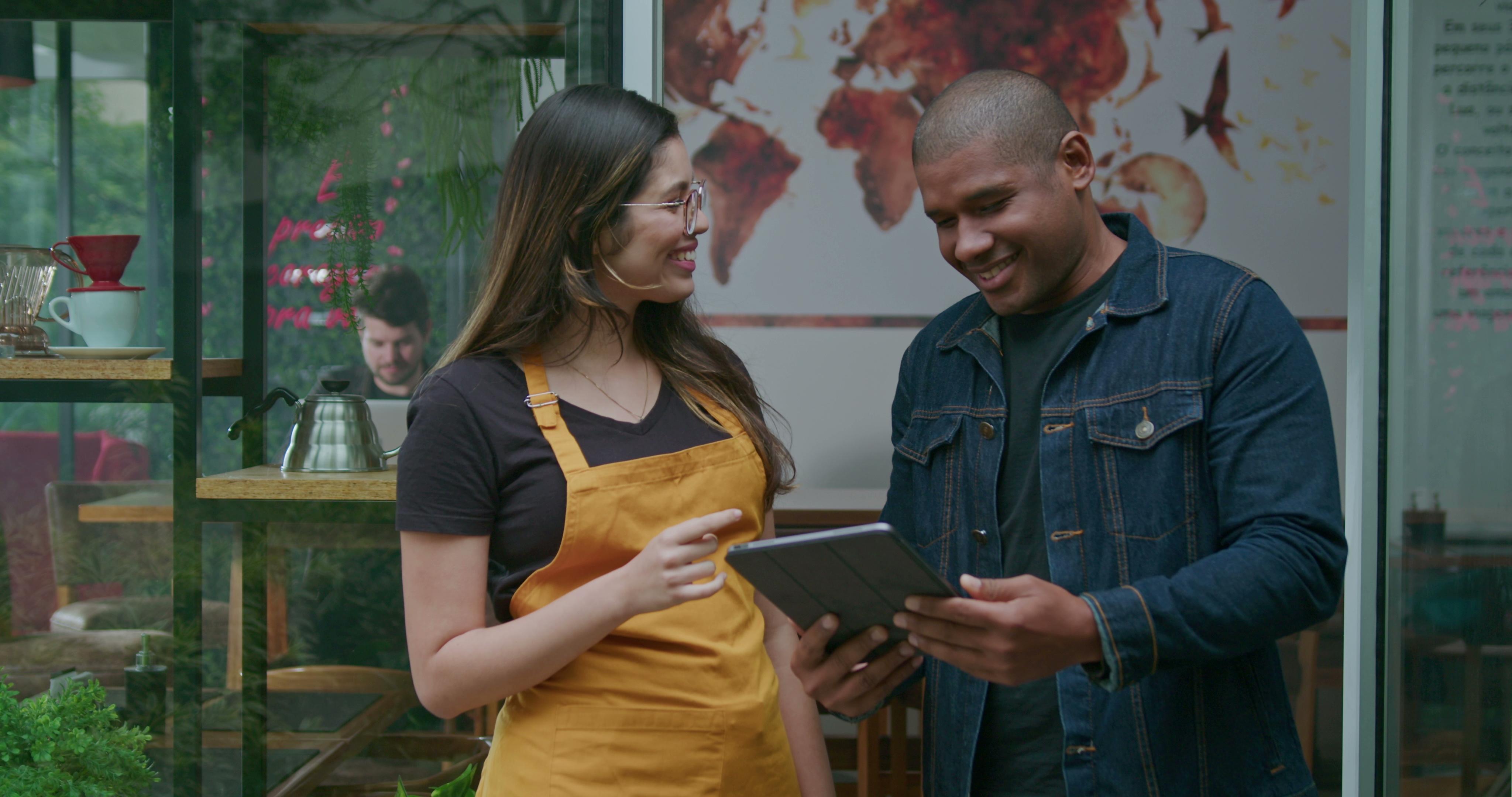 Woman with apron talking with man with tablet