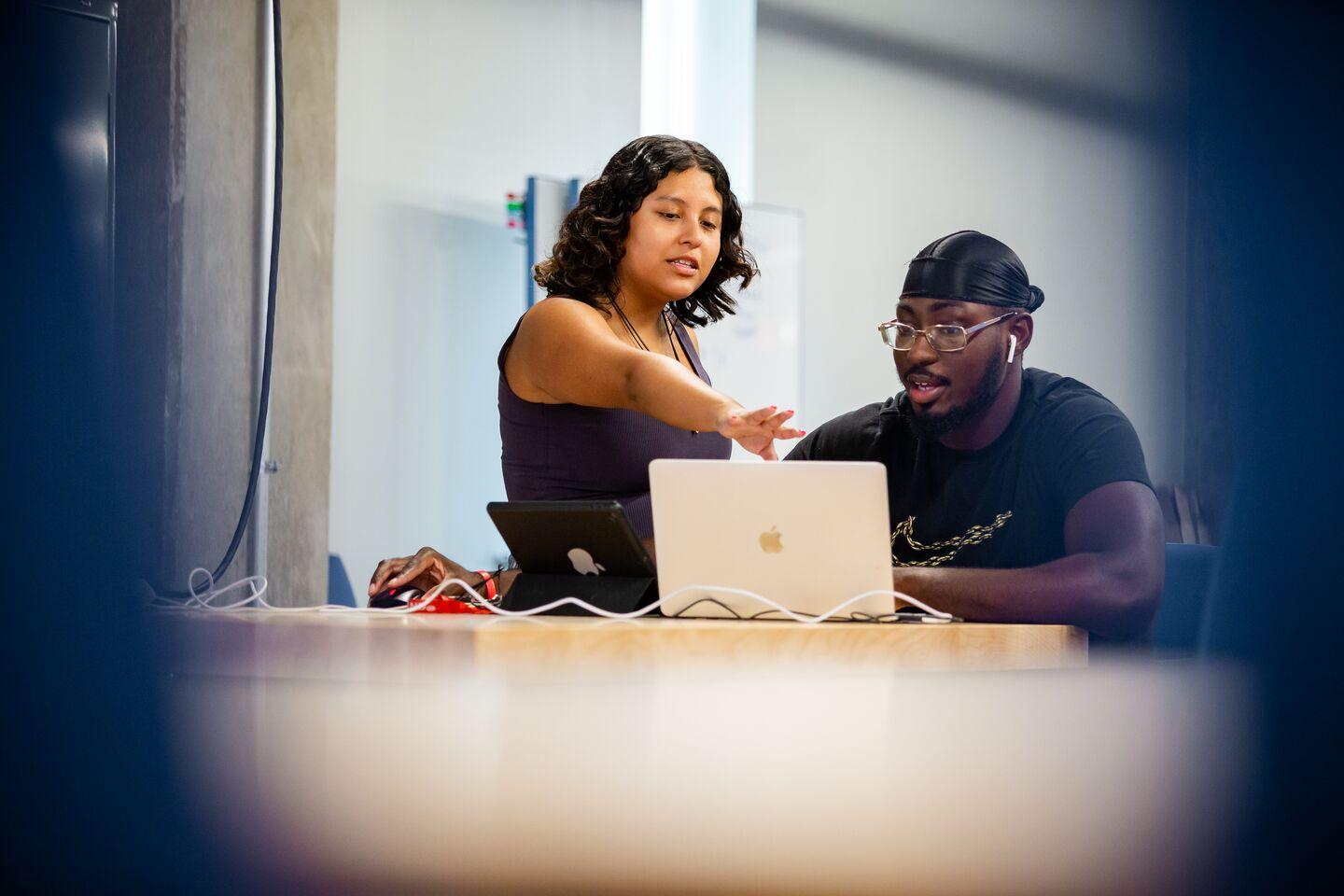 people in front of laptop, one standing and pointing to screen