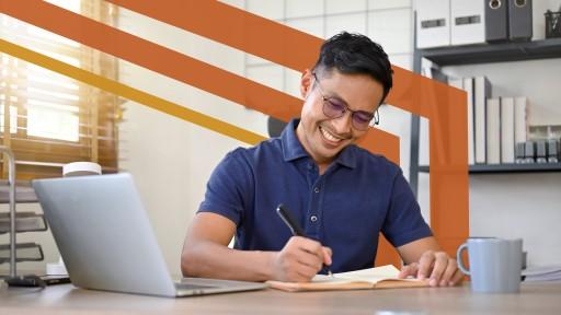 person at desk writing on pad